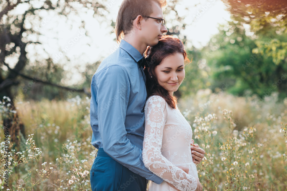 Sunshine portrait of happy bride and groom outdoor in nature location at sunset. Warm summertime