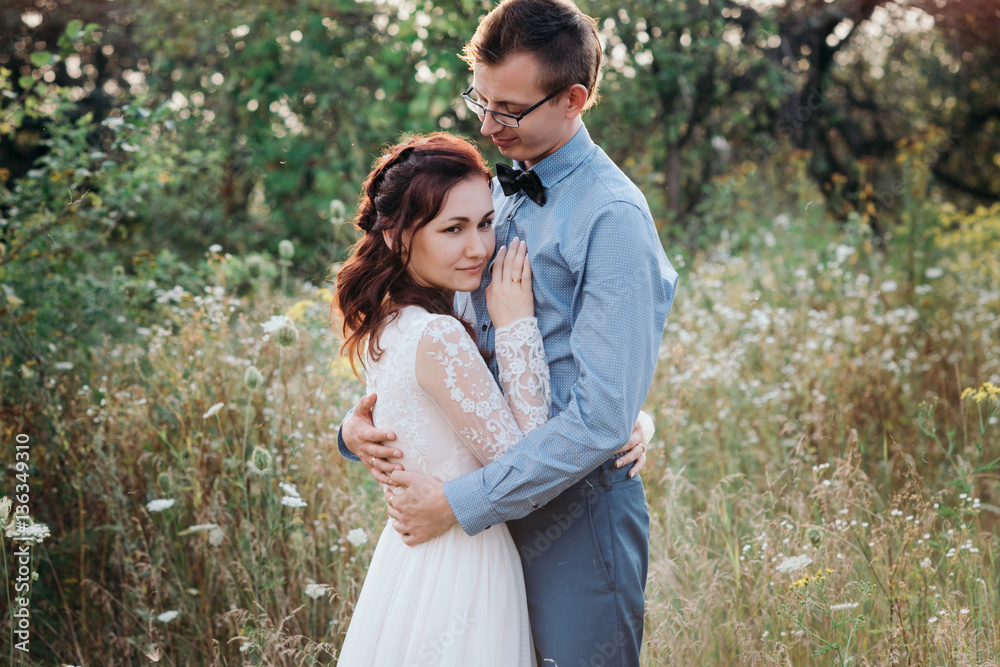Fototapeta premium Sunshine portrait of happy bride and groom outdoor in nature location at sunset. Warm summertime
