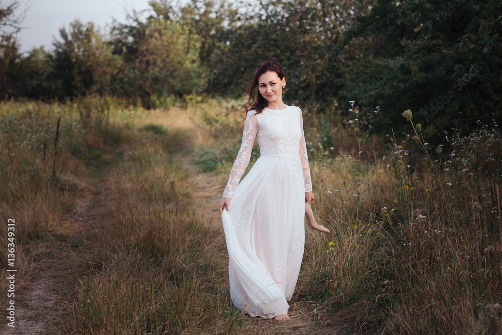 Yong bride spinning in a white dress on the bank on nature.Dress develops in the wind. Happy bride in a wedding dress is spinning. Yong bride spinning in a white dress on the bank on nature.Dress develops in the wind. Happy bride in a wedding dress is spinning.
