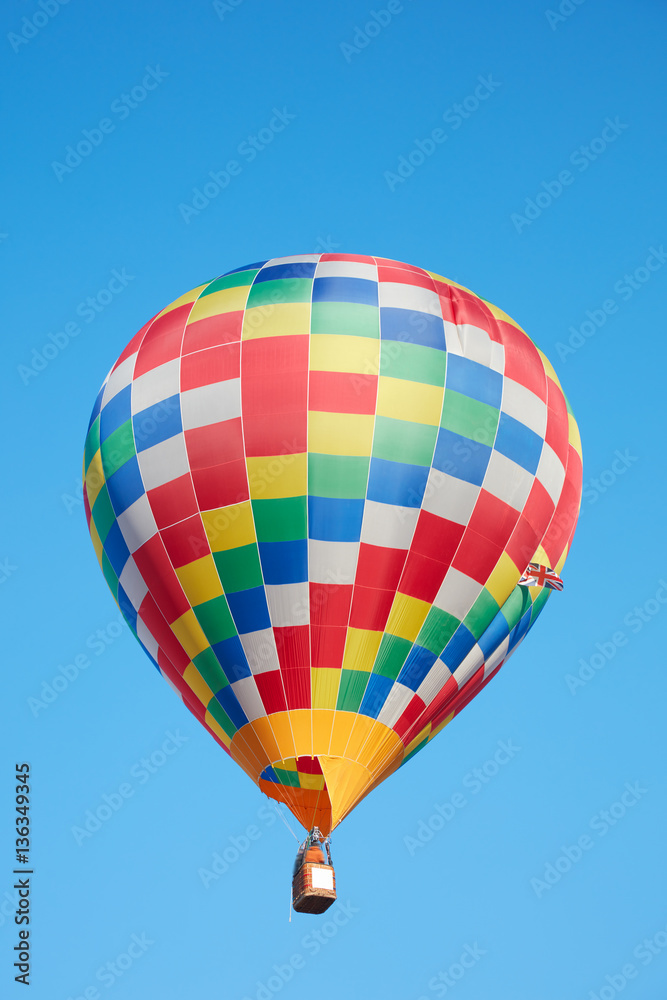 Fototapeta premium Hot air balloon, colorful checkered aerostat on blue sky