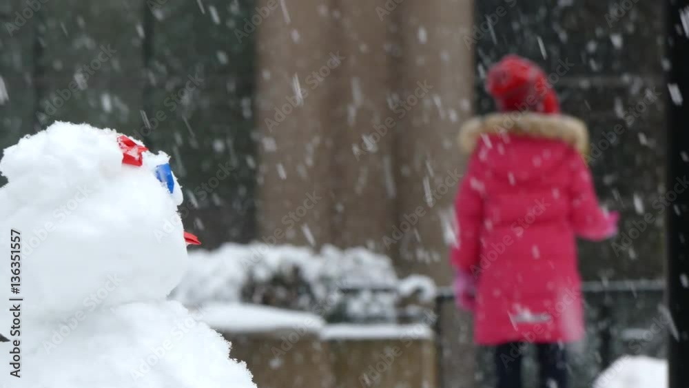 Freshly built snowman girl in wintercoat Freshly built snowman girl in wintercoat