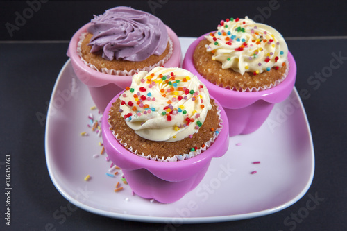the cupcakes with white and violet cream on the black background,