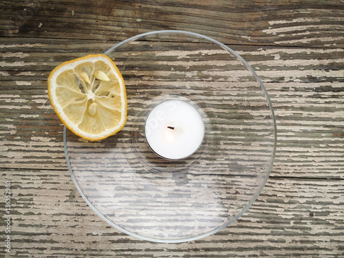 The dried lemon is surrounded of candles on wooden table