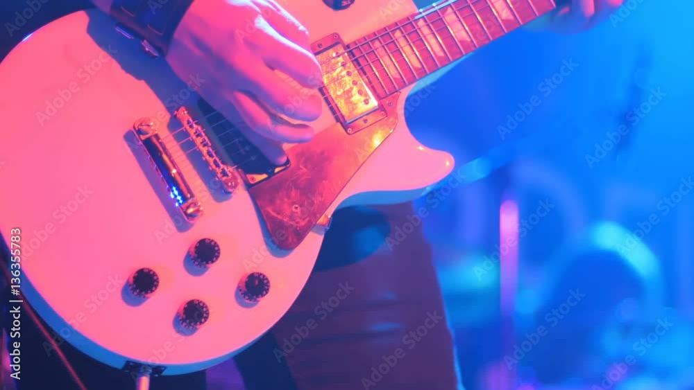 Close-up - man playing on an electronic guitar with mediator on a concert