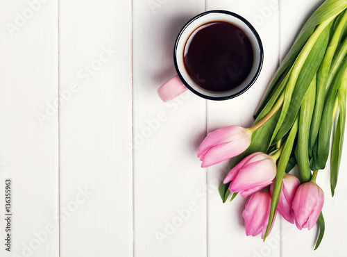 Pink tulips and coffee in a mug on the white table