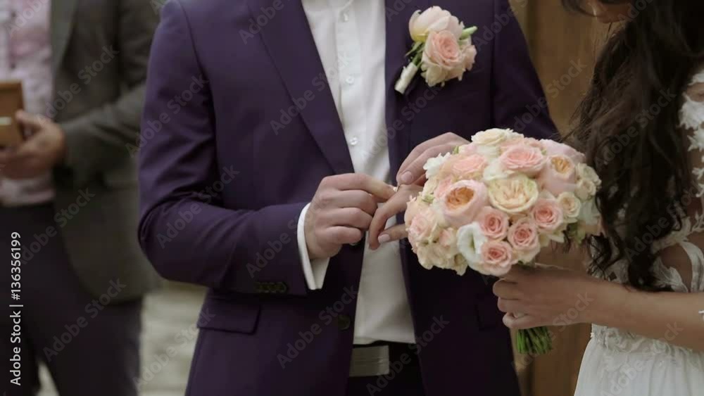 Wedding ceremony: groom puts a ring on bride hand shot