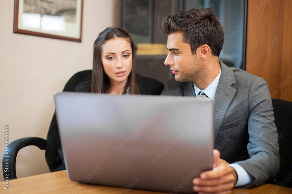 Smiling business people using a laptop computer in their office Smiling business people using a laptop computer in their office