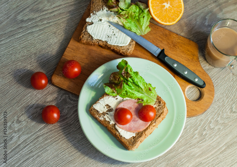 Sandwich with bacon, ham and cheese for breakfast. Coffee cappuccino. On a wooden background