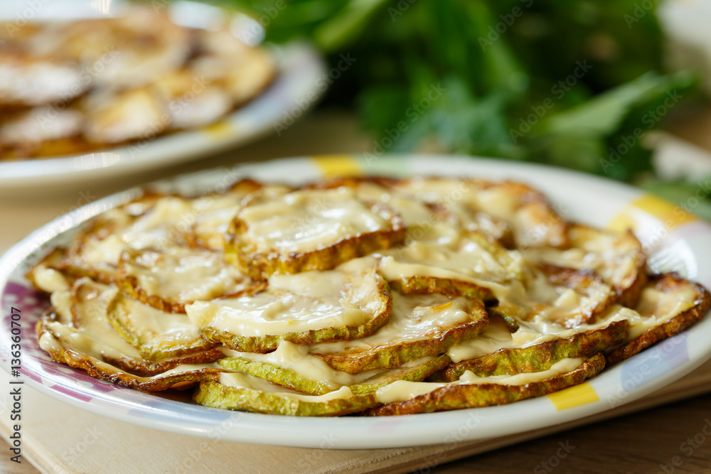 Zucchini chopped and fried slices with mayonnaise on a plate.