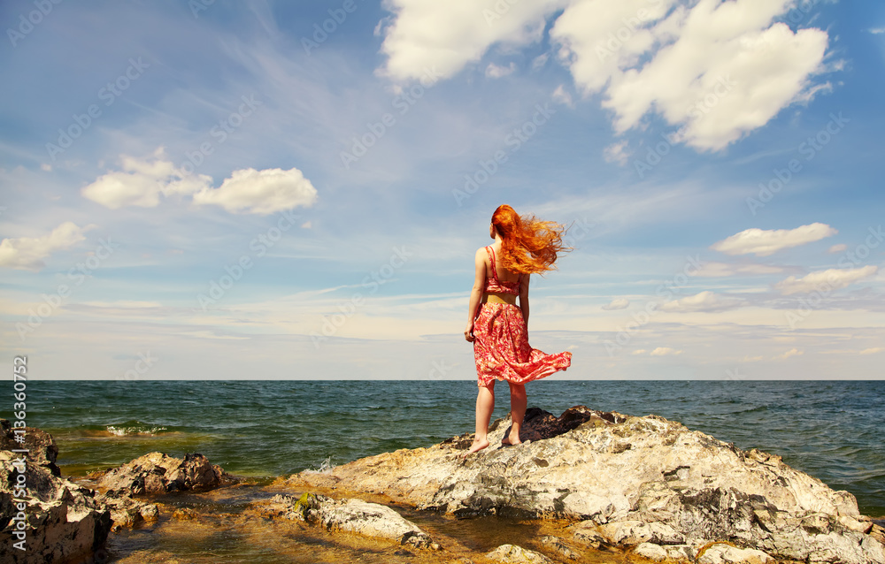 redhead young woman in a dress on the ocean coast