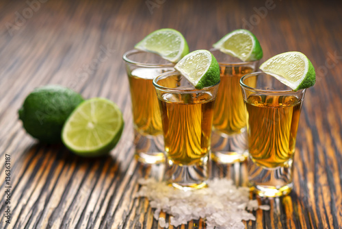 Glasses gold tequila with green lime