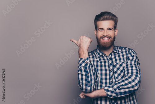 Cheerful toothy bearded stylish man pointing with finger photo