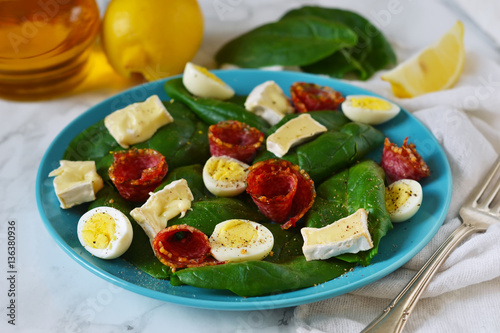 Salad with spinach, brie cheese and quail eggs.