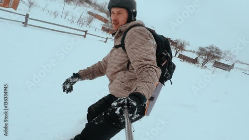 snowboarder taking selfie while climbing mountain. snowboarder rides on the board in the snow and relieves himself