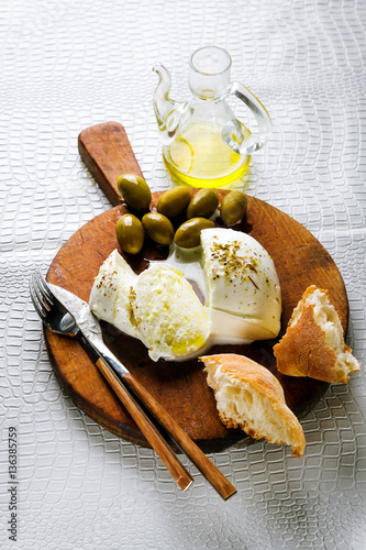 Mozzarella Cheese and Green Olives with bread on cutting board o