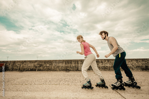 Foto Active young people friends rollerskating outdoor.