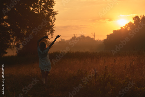 Pretty young woman in field at sunset