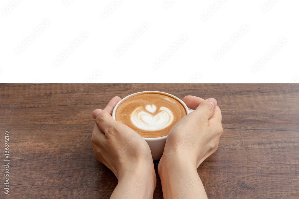 Hand holding coffee cup of latte art on wooden table with white