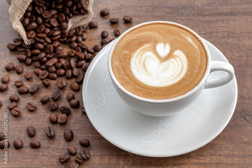 Coffee cup of latte art with coffee beans on wooden background
