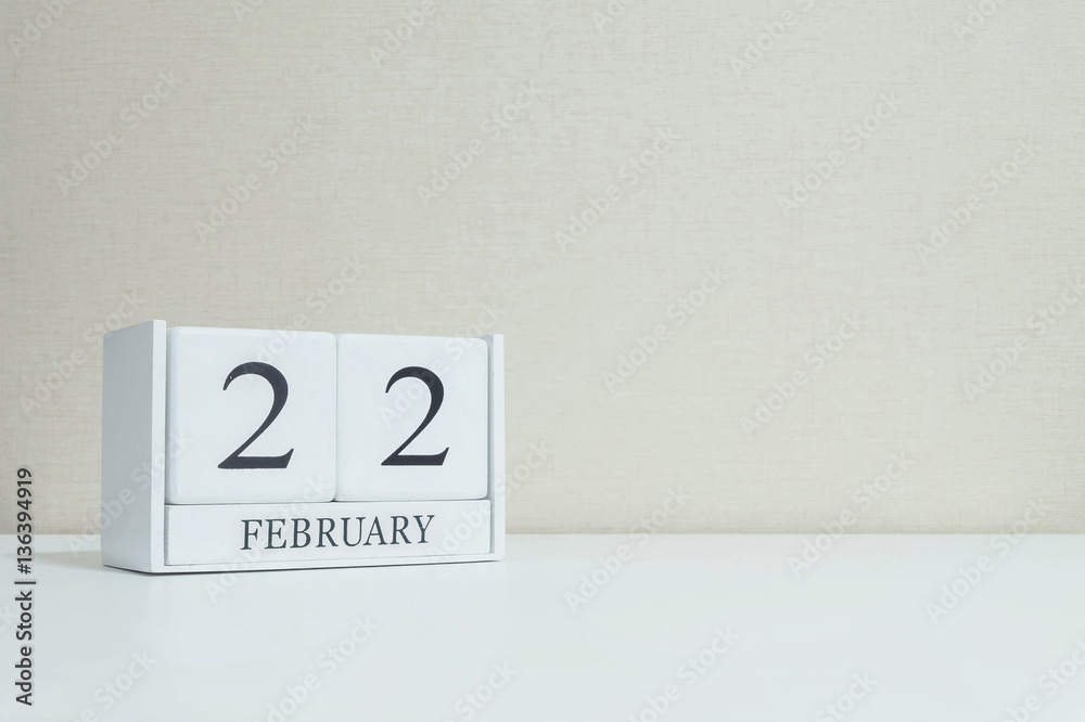 Closeup white wooden calendar with black 22 february word on blurred white wood desk and cream color wallpaper in room textured background with copy space in selective focus at the calendar Closeup white wooden calendar with black 22 february word on blurred white wood desk and cream color wallpaper in room textured background with copy space in selective focus at the calendar