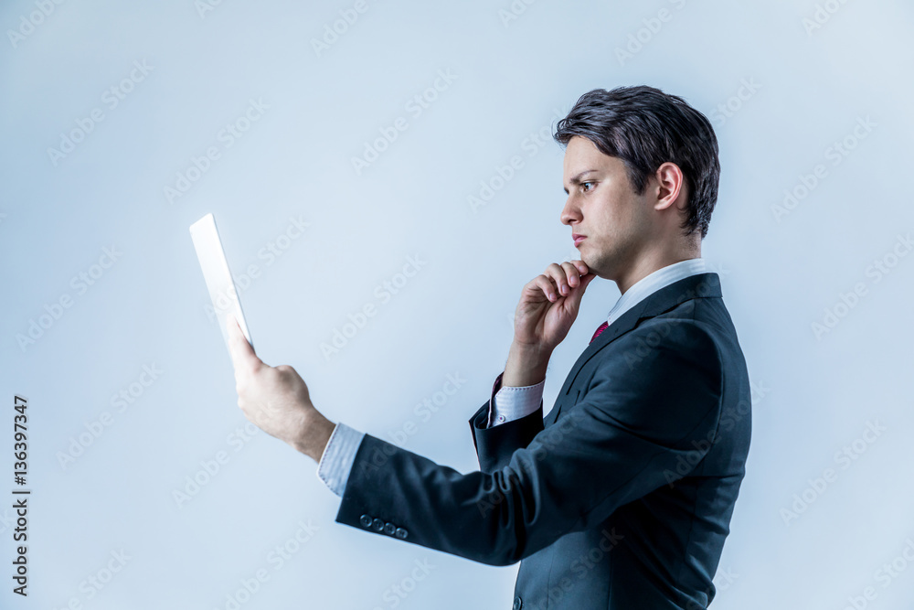 young businessman holding tablet PC and thinking something on white background young businessman holding tablet PC and thinking something on white background