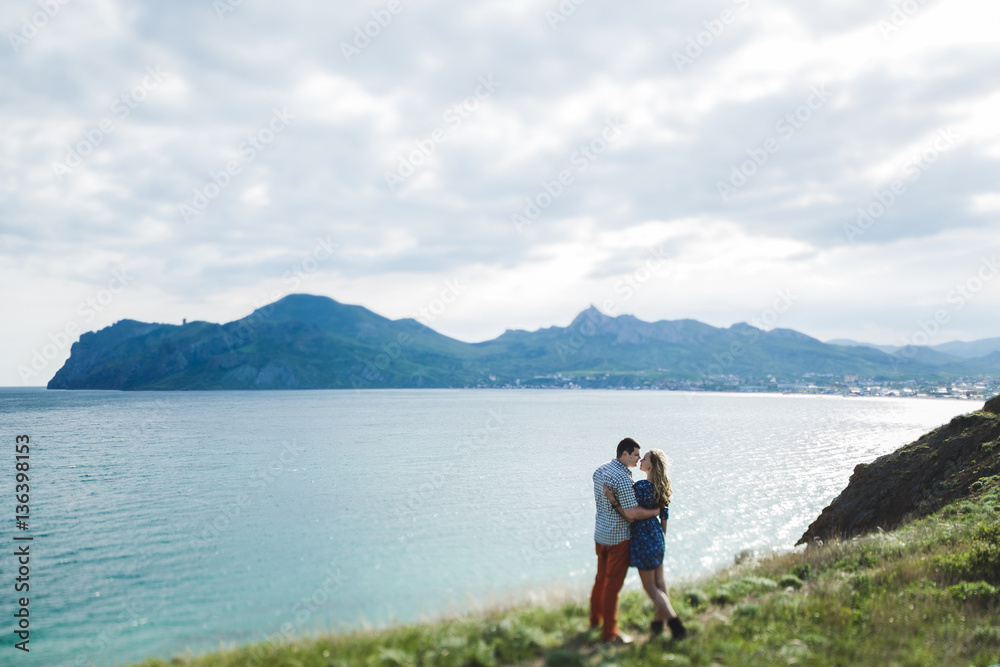 Fototapeta premium Couple walking outdoors by the sea and enjoying beautiful mountain view