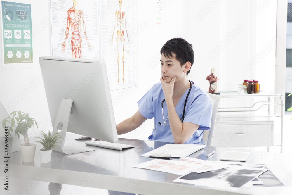 The male doctor is looking at the computer with a sincere look