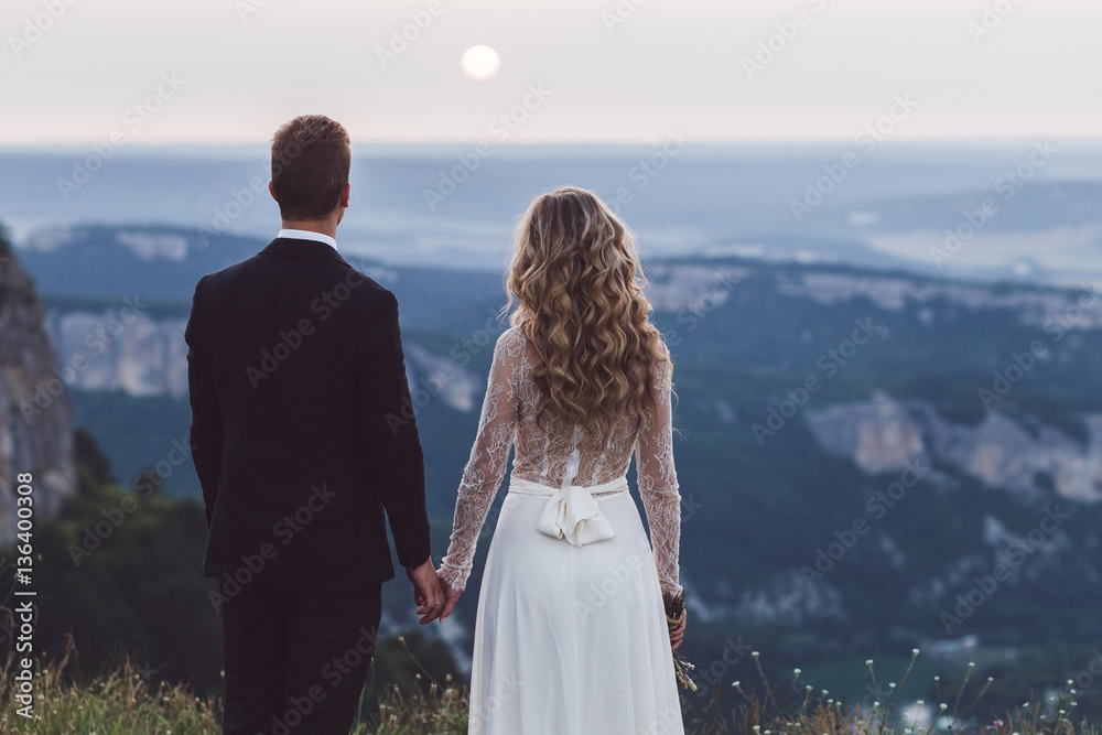 Bride and groom watching sunset in fantastic mountain canyon