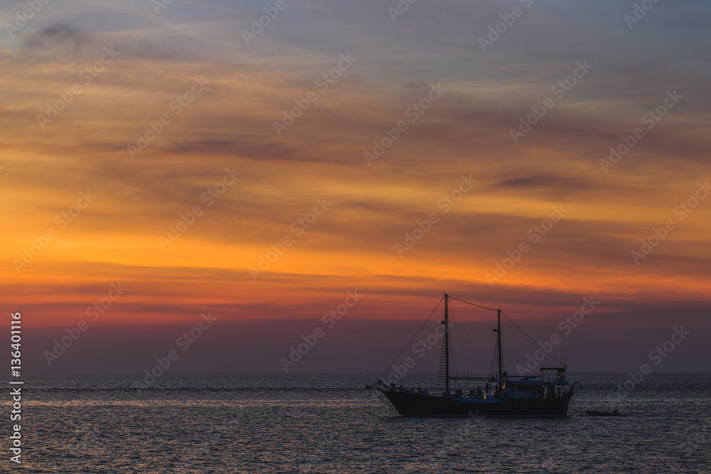Big and vintage wooden pleasure sailboat in sea at sunset. Colorful sunset