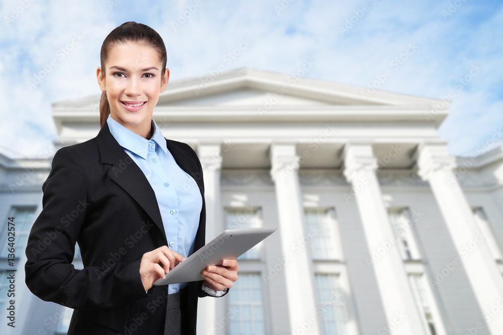 Fototapeta premium Law and justice concept. Young woman with tablet on courthouse background