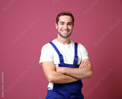 Handsome young worker on color background