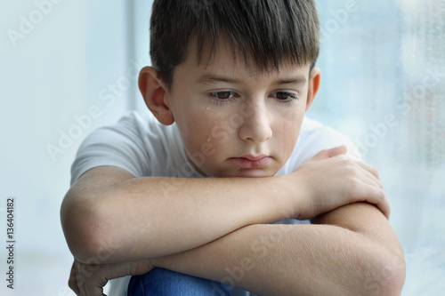 Sad little boy on blurred b...