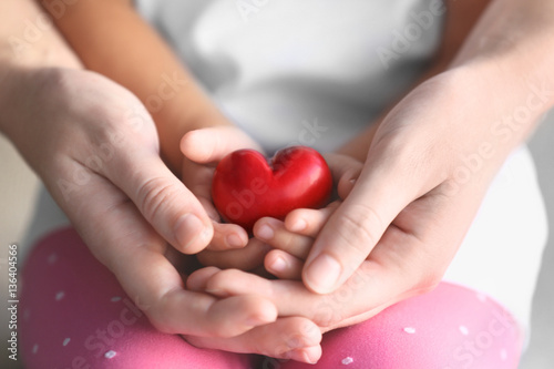 Child and adult person holding small red heart, closeup. Adoption concept © Africa Studio