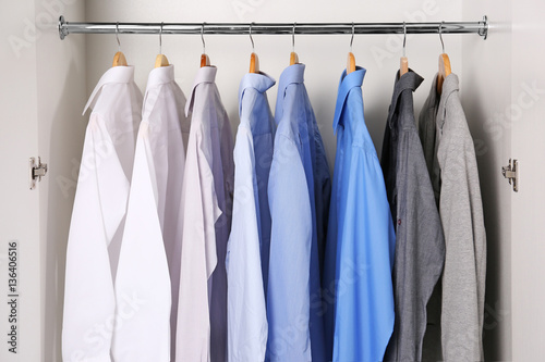 Closeup of hangers with different shirts in wardrobe