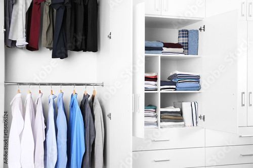 Wardrobe with different clothes at home © Africa Studio