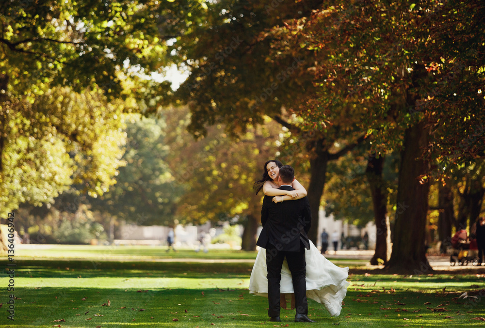 Fototapeta premium Happy bride in the arms of her strong groom