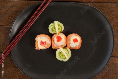 Three nigiri sushi served in black plate with chopsticks