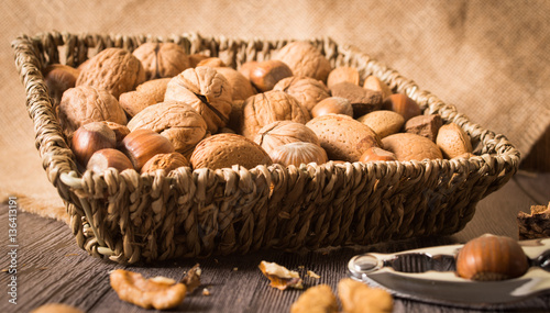delicious assortment of nuts in a woven basket on wooden backgro