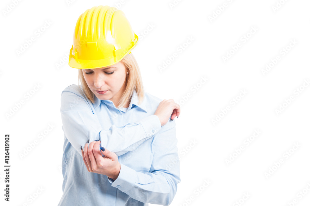 Female architect wearing helmet checking her elbow for injures Female architect wearing helmet checking her elbow for injures