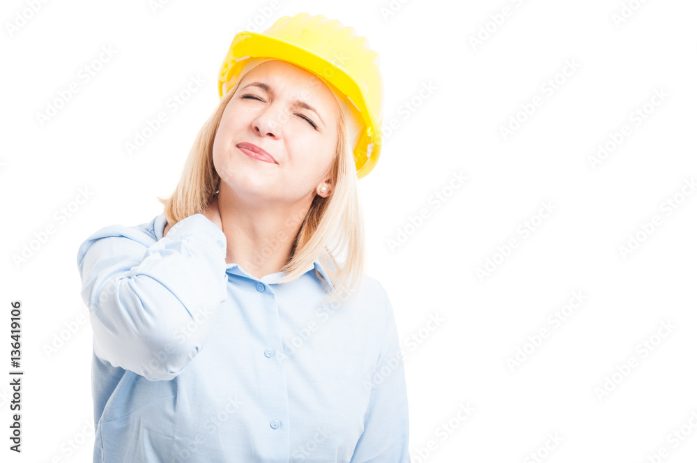 Female engineer wearing helmet making back neck pain gesture