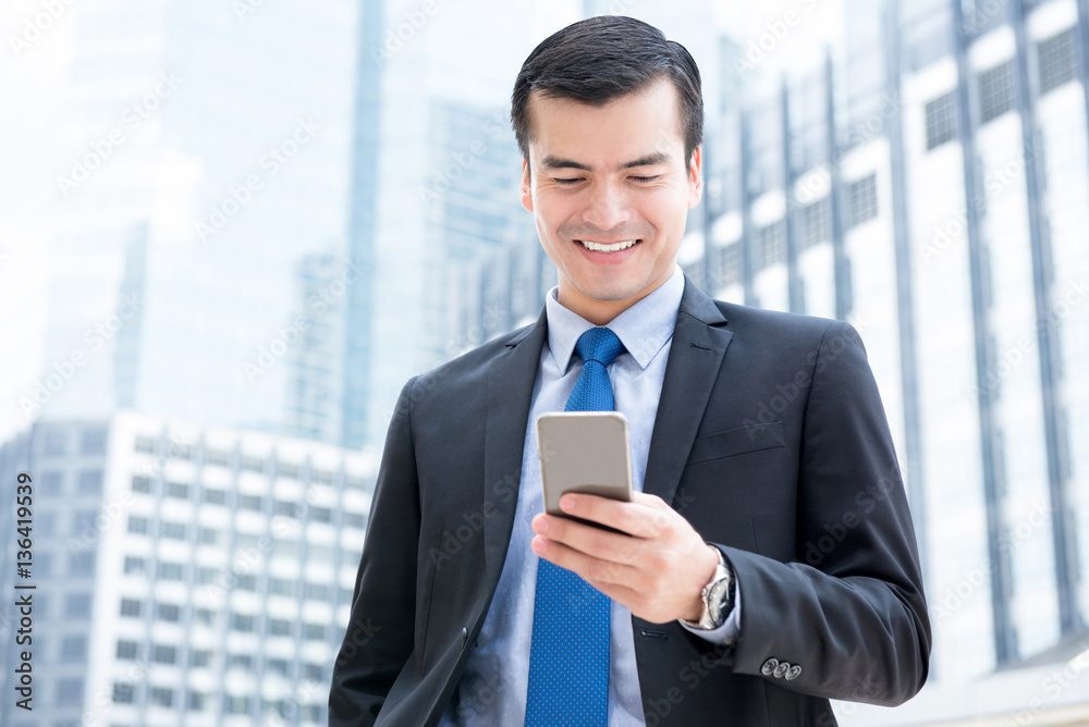 Businessman using smartphone in front of office buildings Businessman using smartphone in front of office buildings