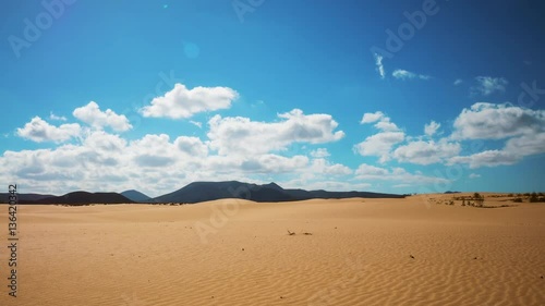 Timelapse shot of cloudscape rolling over desert and mountains. Scenic aerial view of blue sky on sunny day. Idyllic view of wave patterns on sand. 4K resolution.
