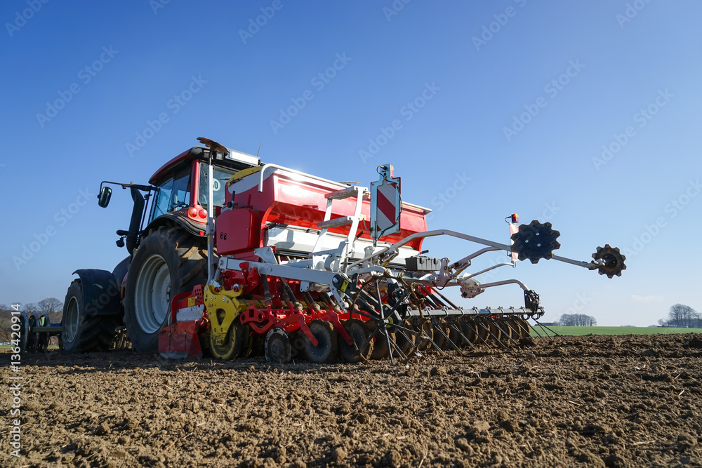 Obraz premium Ackerbau - Frühjahrsbestellung, Schlepper mit Drillmaschine bei der Aussaat