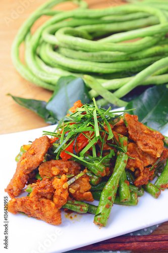 stir fried pork curry lentils on white plate with fresh green sting bean at background. photo
