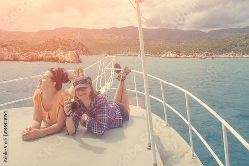Two women with camera lying on the bow of the boat in the sunlight