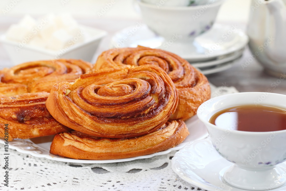 Baked sweet cinnamon rolls with cup of tea Baked sweet cinnamon rolls with cup of tea