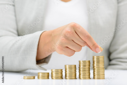 Female hand putting money coin stack growing business, saving money concept. photo