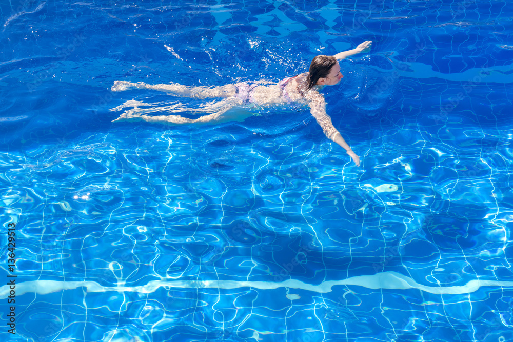 Woman in a bikini floating in swimming pool