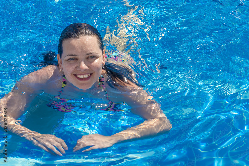 Beautiful brunette woman in a bikini with a smile in the swimming pool