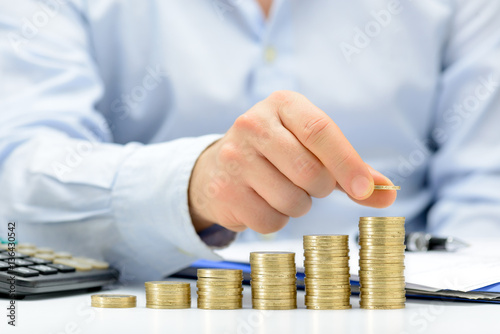Male hand putting money coin stack growing business, saving money concept. photo